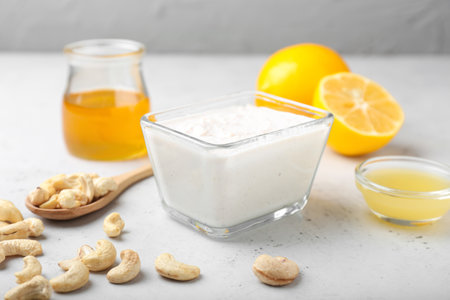 Bowl with cashew sour cream, nuts, honey and lemon juice on light backgroundの写真素材