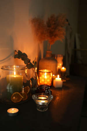 Glowing aroma candles on table in dark roomの写真素材