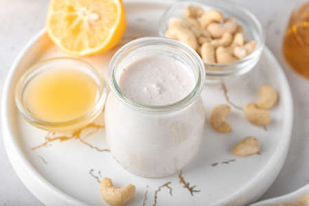 Tray with cashew sour cream, nuts and lemon juice on light background, closeupの写真素材