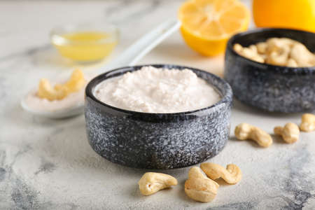 Bowls with cashew sour cream, nuts and lemon juice on light background, closeupの写真素材