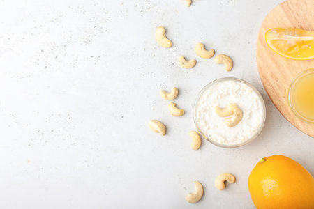Bowl with cashew sour cream, nuts and lemon juice on light backgroundの写真素材