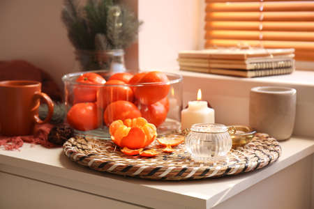 Aroma candles with tangerines on chest of drawers in roomの写真素材