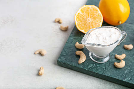 Gravy boat with cashew sour cream, nuts and lemon on light backgroundの写真素材