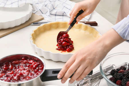 Woman cooking berry pie in kitchenの写真素材