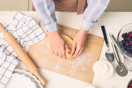 Woman kneading dough on board in kitchenの写真素材
