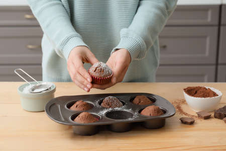 Woman with tasty cupcakes in kitchenの写真素材