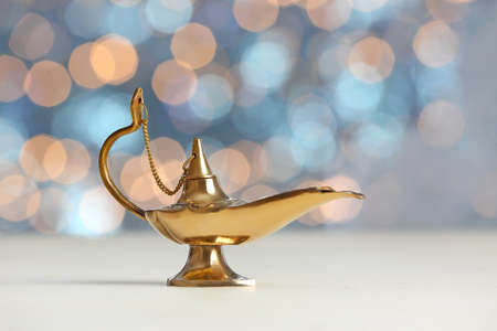 Aladdin lamp of wishes on table against blurred lights