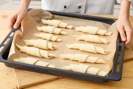 Woman with uncooked croissants in kitchen, closeupの写真素材