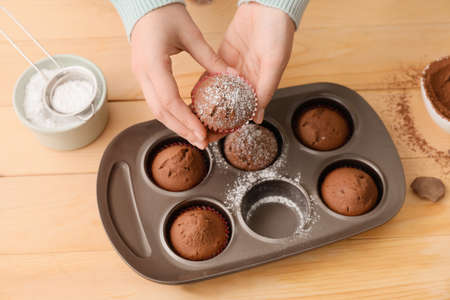 Woman with tasty cupcakes in kitchenの写真素材