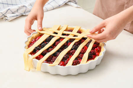 Woman cooking berry pie in kitchenの写真素材
