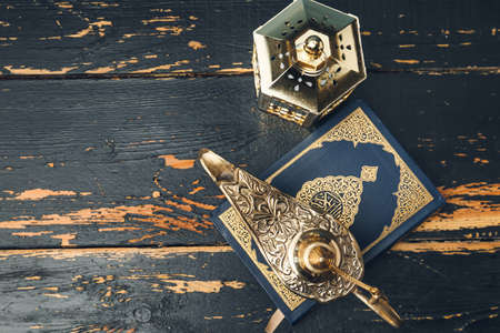Aladdin lamp of wishes with Koran and Muslim lamp on dark wooden background