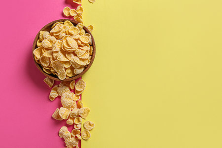 Bowl with tasty cornflakes on color background