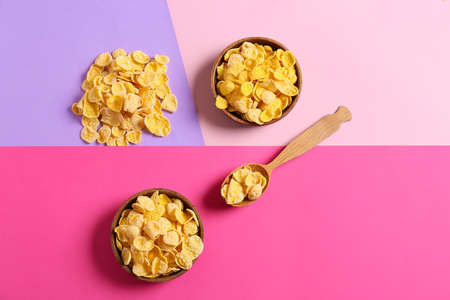 Bowls and spoon with tasty cornflakes on color backgroundの写真素材