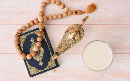 Aladdin lamp of wishes with Koran, glass of milk and tasbih on wooden backgroundの写真素材