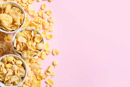 Bowls with tasty cornflakes on color background