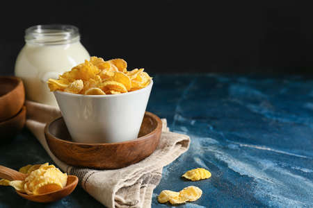 Bowl and spoon with tasty cornflakes on color backgroundの写真素材