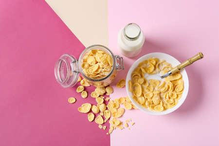 Bottle of milk, bowl and jar with tasty cornflakes on color backgroundの写真素材