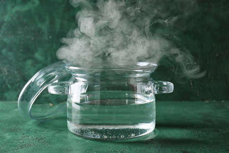 Stylish cooking pot with hot water on color backgroundの写真素材