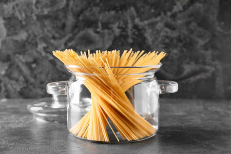 Stylish cooking pot with uncooked pasta on dark backgroundの写真素材