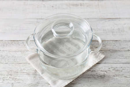 Stylish cooking pot with water on light wooden backgroundの写真素材