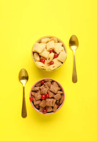 Bowls with tasty corn pillows and cranberries on color background