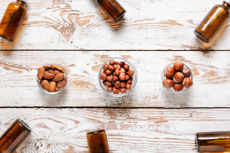 Bowls with different healthy nuts and oil on white wooden backgroundの写真素材