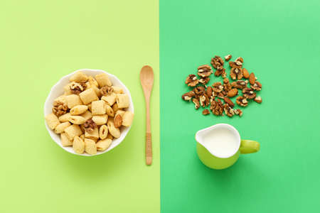 Bowl with tasty corn pillows, milk and walnuts on color backgroundの写真素材