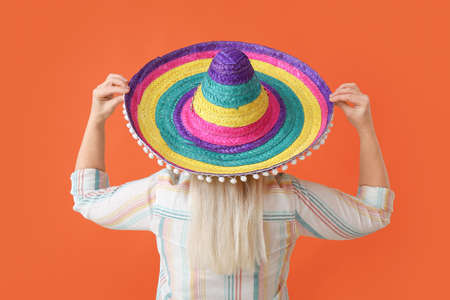 Mature Mexican woman in sombrero hat on color backgroundの写真素材