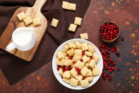 Plate with tasty corn pillows, cranberries and milk on grunge background