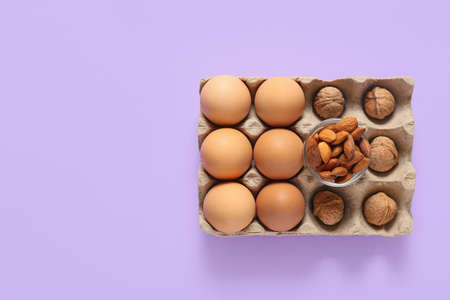 Different healthy nuts and eggs on color background