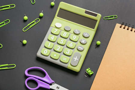 Modern calculator and stationery on dark background