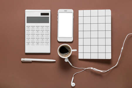 Modern calculator with mobile phone, cup of coffee and stationery on color backgroundの写真素材