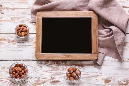 Empty chalkboard with healthy nuts on white wooden backgroundの写真素材