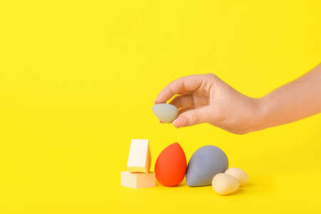 Female hand with stylish makeup sponges on color backgroundの写真素材