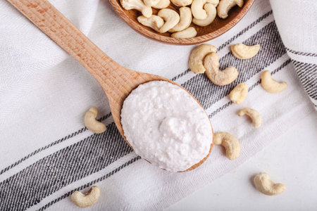 Spoon with sour cream and cashew nuts on light background, closeupの写真素材