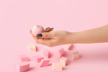 Female hand with stylish makeup sponges on color backgroundの写真素材