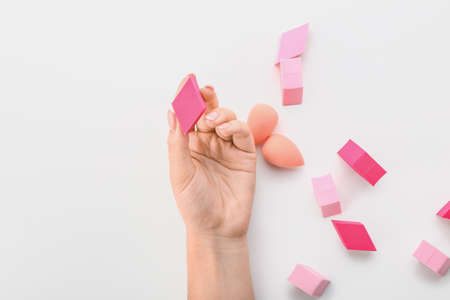 Female hand with stylish makeup sponges on white backgroundの写真素材