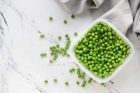 Plastic container with green peas on light backgroundの写真素材