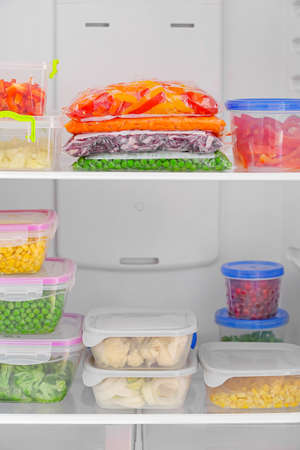 Containers and plastic bags with vegetables in refrigeratorの写真素材