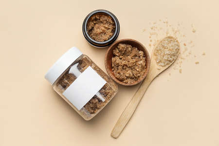 Jars of body scrub and sea salt on color background