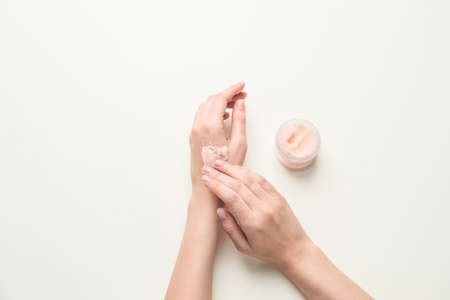 Female hands with body scrub on light background