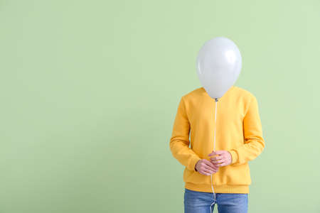 Handsome young man with balloon on color backgroundの写真素材