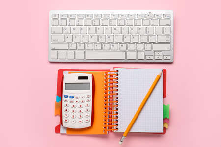 Calculator with notebook and computer keyboard on color backgroundの写真素材
