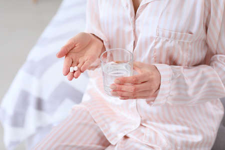 Beautiful young woman taking pills at home, closeupの写真素材