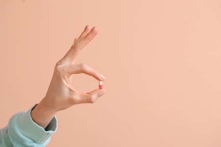 Woman with pill showing OK on color background