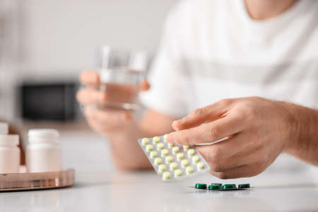 Handsome young man taking pills at homeの写真素材