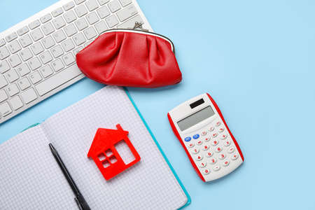 Calculator with model of house, notebook, wallet and computer keyboard on color backgroundの写真素材