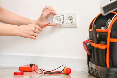Young female electrician repairing socket at homeの写真素材