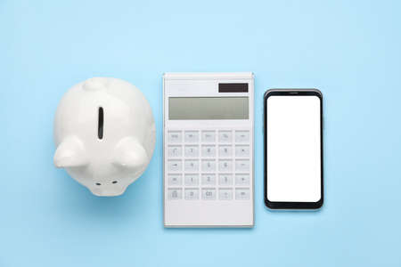 Calculator with mobile phone and piggy bank on color backgroundの写真素材