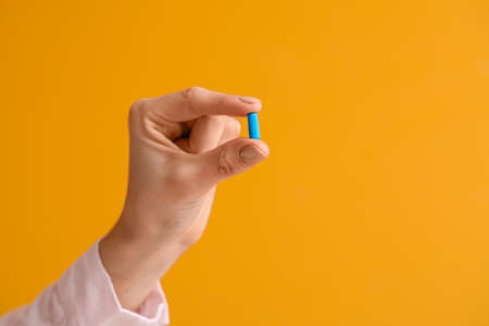 Young woman with pill on color background, closeupの写真素材
